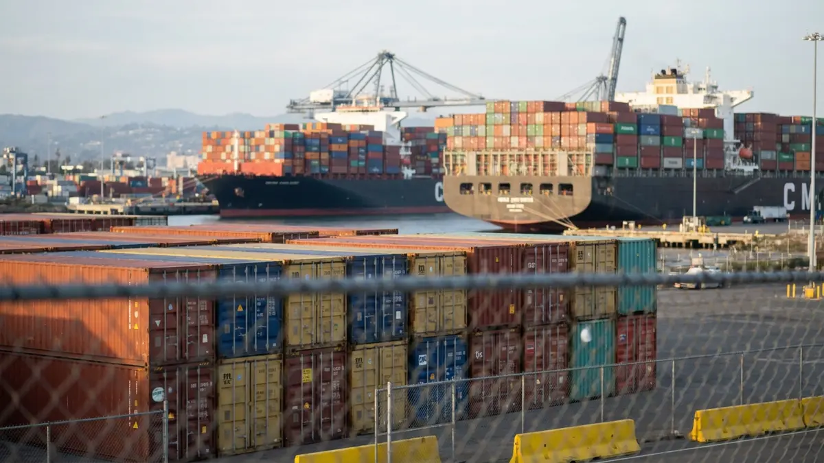 Navios de carga e contêineres em um porto, com um céu nublado, representando desafios no comércio internacional.