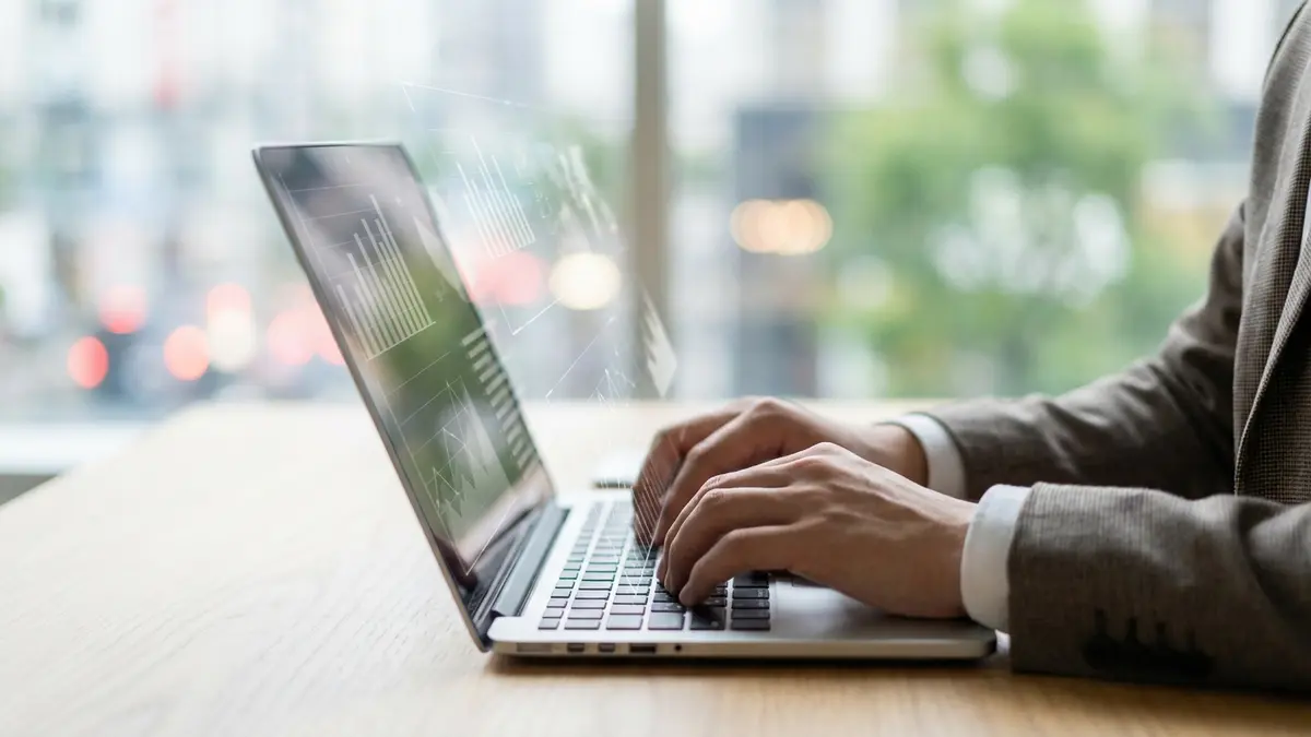 Mãos digitando em um teclado de computador, com elementos gráficos de notas fiscais e impostos flutuando ao redor.